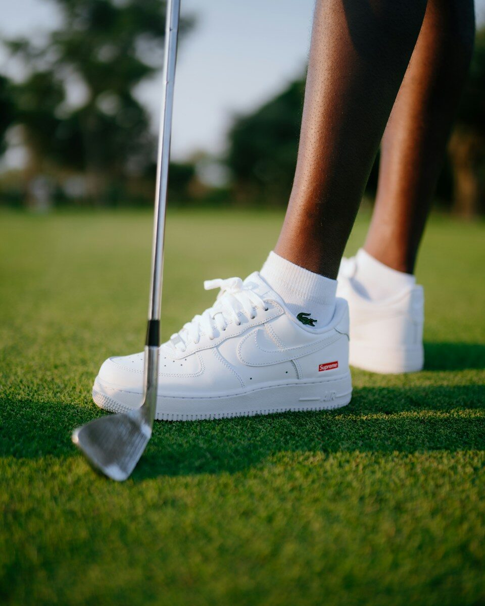 Golfer wearing white sneakers on green grass